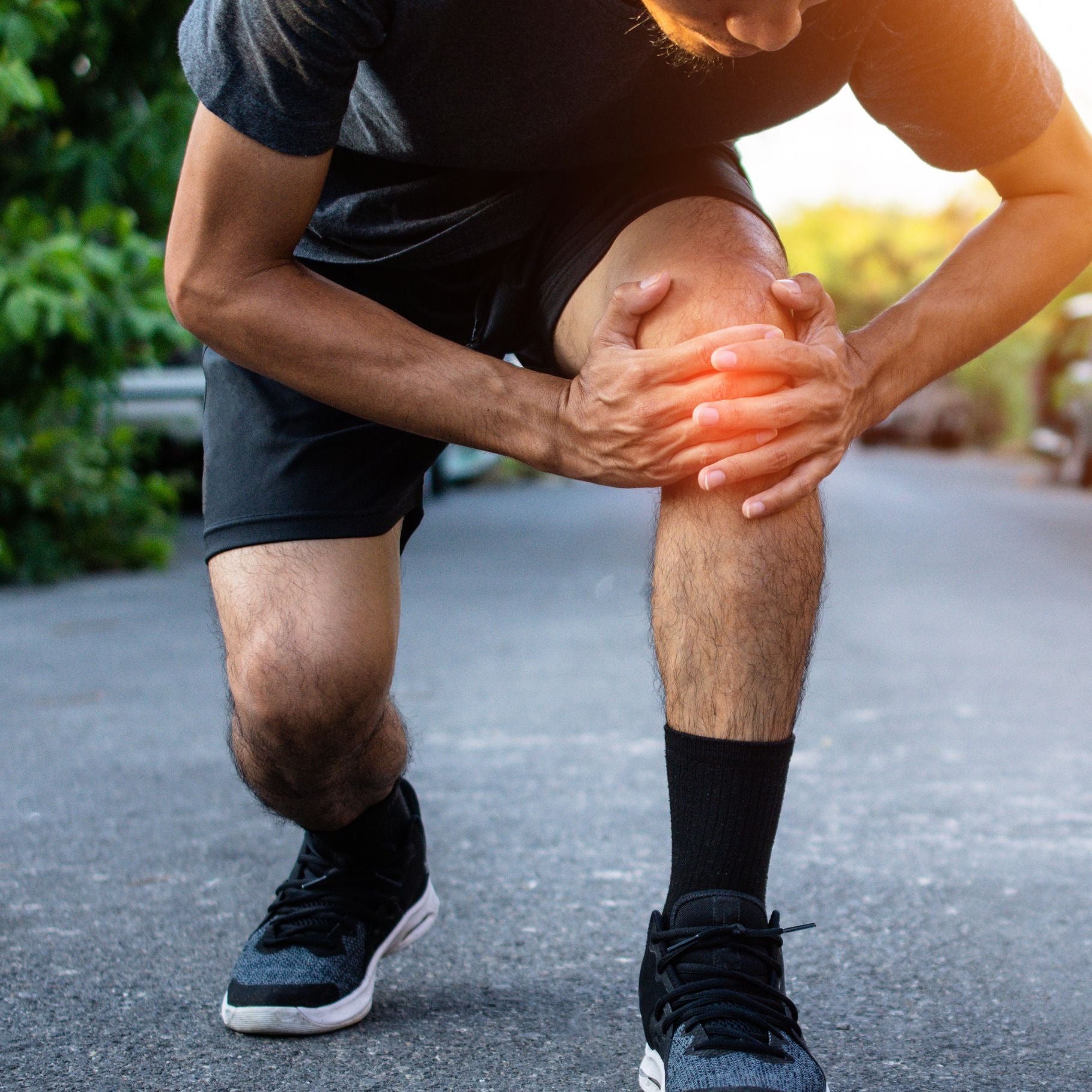 Ein Mann hält sein schmerzendes Knie, was auf Beschwerden hinweist, die mit Arthrose verbunden sein könnten.