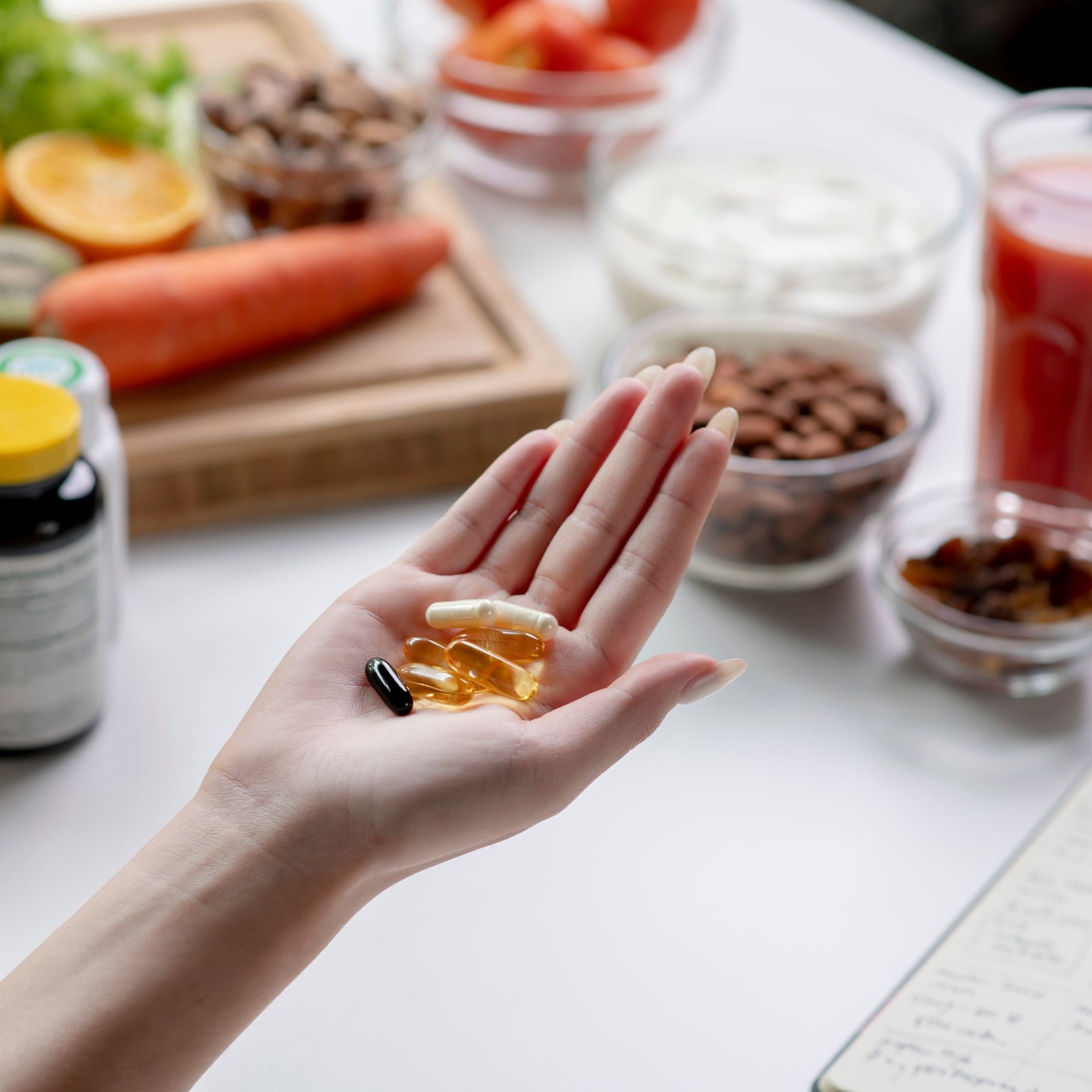 Eine Hand mit verschiedenen Nahrungsergänzungsmitteln vor einem Hintergrund mit gesunden Lebensmitteln, was den Nutzen von Supplementen als Ergänzung zur Ernährung zeigt.